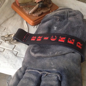 May include: Black leather keychain with red lettering that reads "BRICKER".