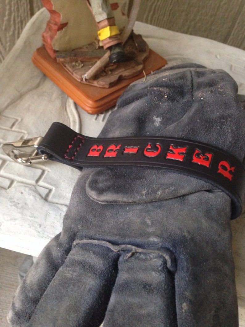 May include: Black leather keychain with red lettering that reads "BRICKER".
