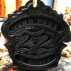 May include: Black leather firefighter patch with the text "SCFD Fern Park 272 S. Burke" embossed on it.