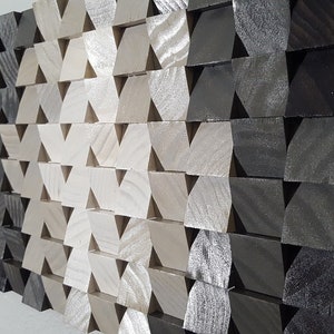 May include: A wall art piece made of wood with a geometric pattern of triangles. The triangles are arranged in a gradient pattern, starting with black and transitioning to white.