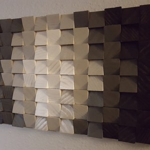 May include: A wall art piece made of wood blocks in various shades of gray, from dark to light, arranged in a geometric pattern.