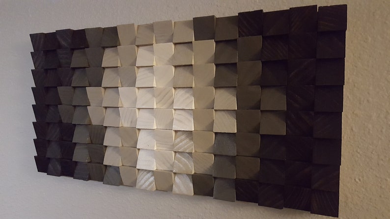 May include: A wall art piece made of wood blocks in various shades of gray, from dark to light, arranged in a geometric pattern.