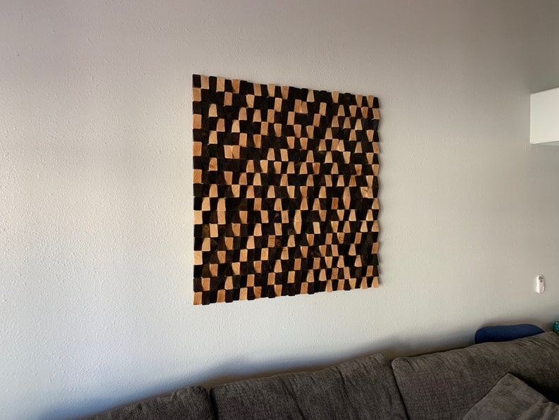 May include: A wall-mounted geometric art piece made of wood. The piece is composed of a grid of squares, each of which is made up of two triangles. The triangles are alternating colors of black and brown.