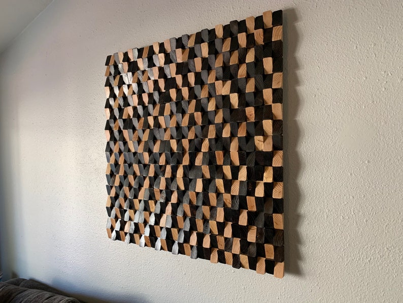 May include: A wall art piece made of wood with a geometric pattern. The wood is stained in two shades, black and brown, creating a checkered pattern.