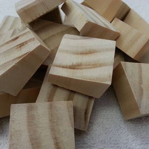 May include: A pile of unfinished, light brown wooden blocks. The blocks are all roughly the same size and shape, and they are arranged in a random order.