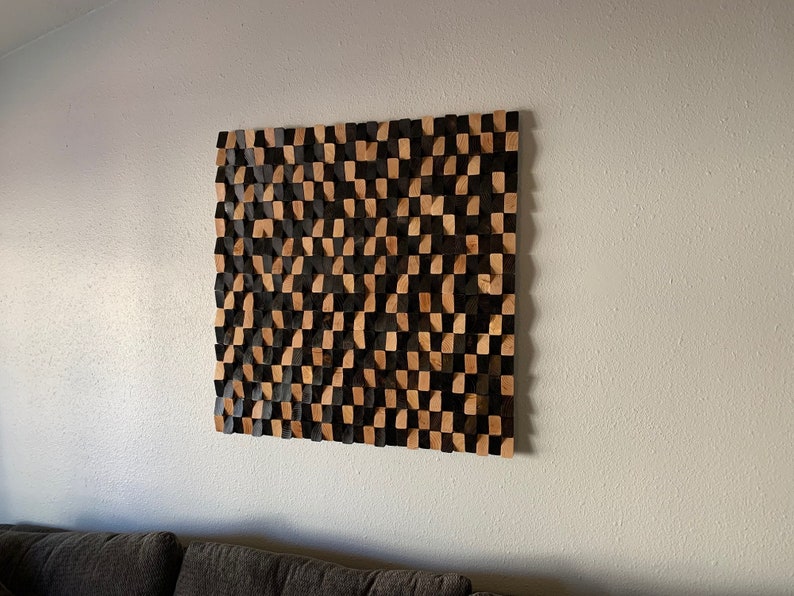 May include: A wall-mounted acoustic panel made of wood blocks in a checkerboard pattern of black and natural wood.