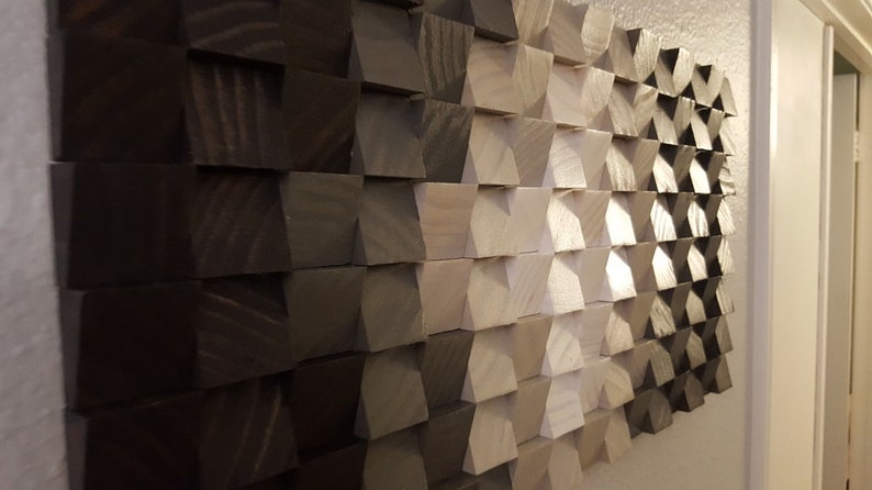 May include: A wall art piece made of wood blocks in various shades of brown and white. The blocks are arranged in a geometric pattern, creating a modern and abstract design.