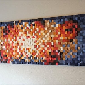 May include: A large abstract wall art piece made of wood blocks. The blocks are arranged in a pattern of blue, orange, red, and white. The piece is mounted on a wall.