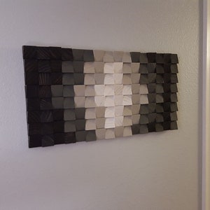 May include: A wall art piece made of wood with a geometric pattern in shades of black, gray, and white.
