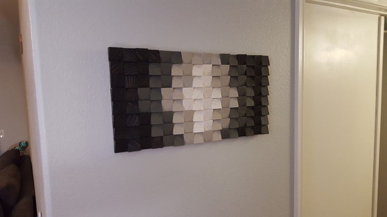 May include: A wall art piece made of wood with a geometric pattern in shades of black, gray, and white.