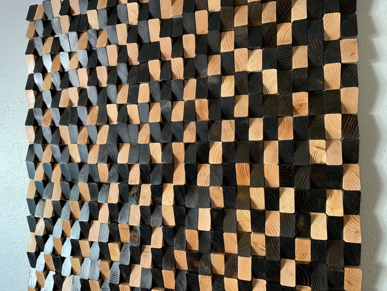 May include: A wall art piece made of wood blocks in a checkered pattern. The blocks are stained in two shades of brown, creating a visually interesting texture.