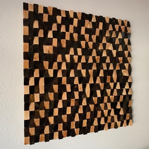 May include: A wall art piece made of wood blocks in a checkered pattern. The blocks are stained in shades of brown and black, creating a geometric design.
