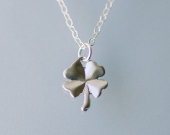 May include: A silver necklace with a four-leaf clover pendant.