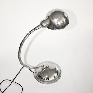 May include: A chrome desk lamp with a flexible gooseneck arm and a round, dome-shaped shade.