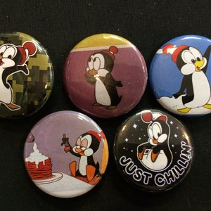 May include: Set of six round button pins featuring a cartoon penguin in various poses and settings. The pins have a variety of backgrounds, including camouflage, blue sky, and a plate of pancakes. One pin features the text "Just Chillin".