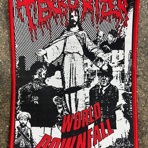 May include: Embroidered patch with a red border featuring a black and white graphic. The design includes the word "TERRORIZER" in red dripping font above a central figure with outstretched arms. Below, the words "WORLD DOWNFALL" are in red.