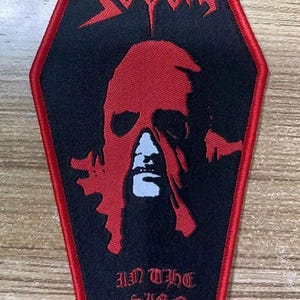 May include: Black and red embroidered patch shaped like a coffin with the band name "SODOM" and the text "IN THE SIGN OF EVIL".