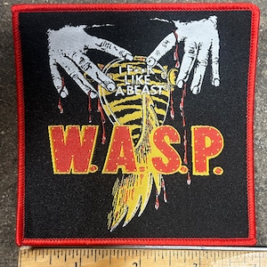 May include: Black and red embroidered patch with a yellow and black striped heart with the text "I F*K LIKE A BEAST" and the band name "W.A.S.P." in red and yellow letters.