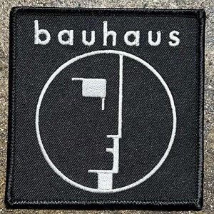 May include: Black and white embroidered patch with the word "bauhaus" and a stylized face design.