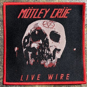 May include: A black and red embroidered patch with a skull and crossbones design. The text "MÖTLEY CRÜE LIVE WIRE" is embroidered in red.
