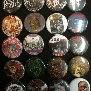 May include: A collection of 20 round metal pinback buttons featuring various band logos and artwork. The buttons are black, white, red, blue, and green. Some of the bands featured include Napalm Death, Repulsion, Terrorizer, and S.O.B.