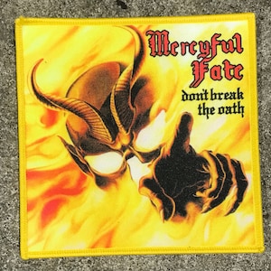 May include: A yellow patch with a black and white image of a demon's face with horns. The text "Mercyful Fate" is in black letters above the image. Below the image is the text "don't break the oath" in black letters.