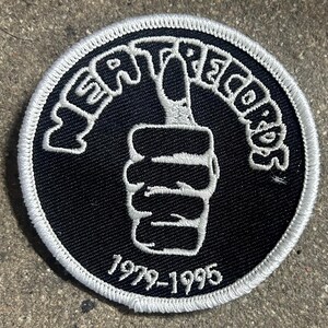 May include: A black and white embroidered patch with a thumbs up gesture and the text "Gear Records 1979-1995".