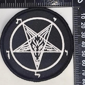 May include: Round black patch with a white pentagram design inside a white circle. The pentagram features a goat's head. The patch has a black border and is likely an iron-on or sew-on patch for clothing or accessories.