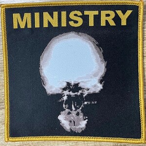 May include: Square black patch with the word "MINISTRY" in gold letters at the top. The patch features a white and light blue image of a mushroom cloud. The patch has a gold border.