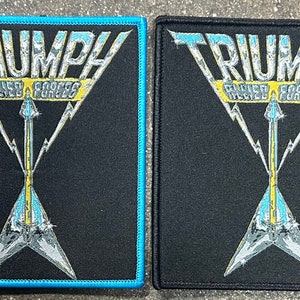 May include: Two black fabric patches with blue stitching. Both patches feature a white and yellow graphic of a guitar with the word "TRIUMPH" and the words "Allied Forces" above the guitar.
