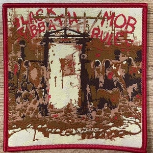 May include: Black Sabbath band patch with the text "Black Sabbath Mob Rules" in red and white lettering on a brown and white background.