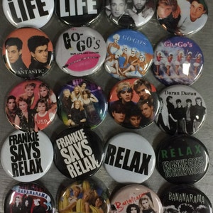 May include: A collection of 16 round buttons featuring various 1980s pop culture icons and bands. The buttons feature images of bands like Duran Duran, Go-Gos, and Frankie Goes to Hollywood, as well as phrases like "Choose Life" and "Relax".