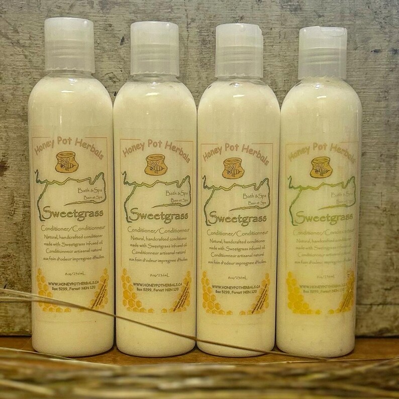 K&ouml;nnte beinhalten: Vier wei&szlig;e Plastikflaschen mit Sweetgrass-Conditioner von Honey Pot Herbals. Jede Flasche hat einen wei&szlig;en Deckel und ein Etikett mit Text und einem Bienenwaben-Design. Die Flaschen sind 236 ml.