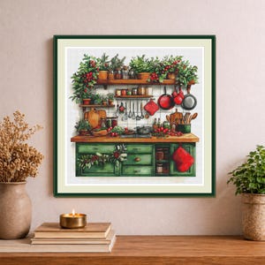 May include: A framed cross-stitch artwork depicting a kitchen scene with green cabinets, wooden countertops, and shelves filled with jars, plants, and hanging cookware. The illustration features red accents, including berries, tomatoes, and a red oven mitt.