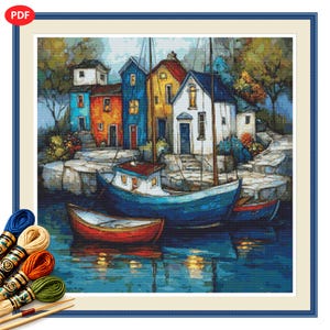 May include: A cross-stitch pattern featuring a coastal scene with colorful houses in blue, red, yellow, and white along a rocky shore. Two boats, one blue and one red, float on the water. Several skeins of embroidery thread in blue, tan, orange, and green are included.