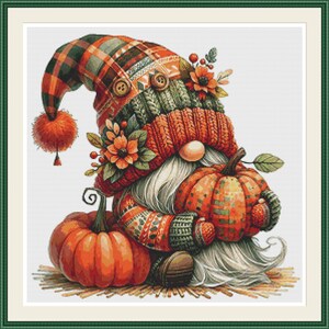 May include: A cross-stitch pattern featuring a gnome wearing a plaid and knit hat with a pom-pom, holding a pumpkin. The gnome has a long white beard, a round nose, and is decorated with orange flowers and berries, with another pumpkin nearby.