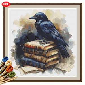 May include: A cross-stitch pattern featuring a black raven perched atop a stack of four weathered books. The background consists of abstract watercolor splashes in shades of blue, brown, and cream. Several loose pages are scattered at the base.