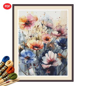 Peut inclure: Motif de point de croix floral à l'aquarelle encadré, représentant des fleurs colorées dans des tons orange, rose et bleu. L'œuvre est dans un cadre marron. Fils à broder et aiguilles visibles en bas à gauche. L'image a une étiquette PDF.