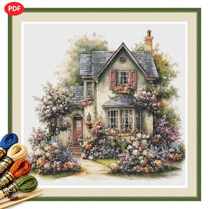 May include: A cross-stitch pattern featuring a two-storey house with a grey roof, light-coloured walls, and red shutters, surrounded by dense, colourful flower bushes and trees. Several skeins of embroidery thread in blue, tan, orange, and green are visible.