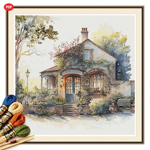 May include: A cross-stitch pattern featuring a watercolor-style cottage with climbing vines, a front porch, and a bench. The scene includes a tall tree, a street lamp, and a stone foundation. Four skeins of embroidery floss in blue, tan, orange, and green.