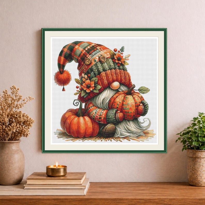 May include: A framed wall art print featuring a whimsical gnome wearing a plaid hat with a pom-pom, adorned with orange flowers and buttons. The gnome has a long white beard and is holding a small pumpkin, with a larger pumpkin resting nearby.