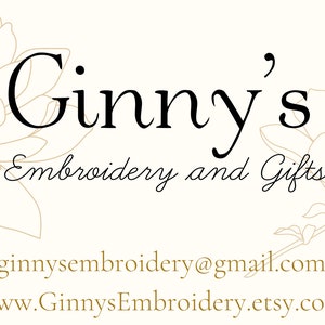 May include: A logo featuring the black text Ginny's Embroidery and Gifts centered above an email address and website URL. The design is framed by two light brown line-art illustrations of magnolia flowers on a cream-colored background.