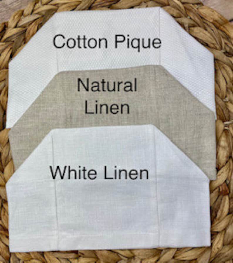 Op de afbeelding: Drie stoffen stalen verticaal gerangschikt. De bovenste staal is wit katoen piqu&eacute; met een geweven textuur. De middelste staal is beige natuurlijk linnen. De onderste staal is wit linnen. Elk stuk heeft een gevouwen, hoekige bovenrand.