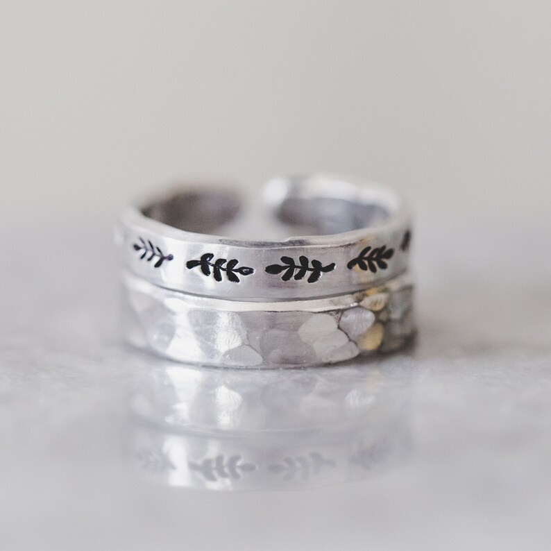 Puede incluir: Un anillo de plata con textura martillada y una banda con un dise&ntilde;o de hojas repetido.
