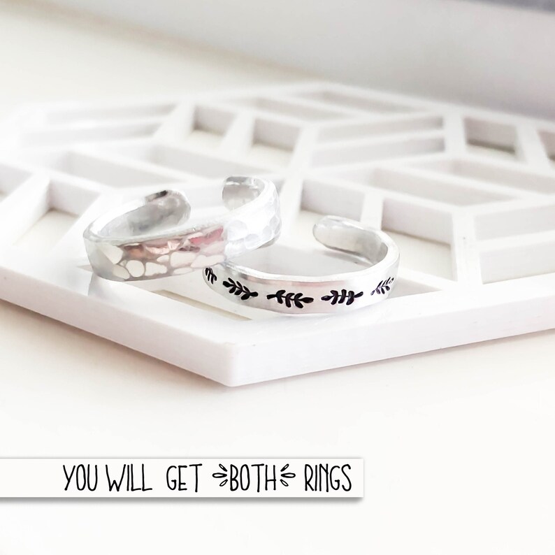 Puede incluir: Dos anillos de plata, uno con textura martillada y el otro con un delicado dise&ntilde;o de hojas. El texto "YOU WILL GET BOTH RINGS" es visible debajo de los anillos.