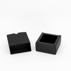 May include: An open black gift box with a lid. The box is made of cardboard and has a smooth finish.