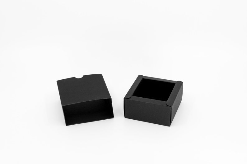 May include: An open black gift box with a lid. The box is made of cardboard and has a smooth finish.