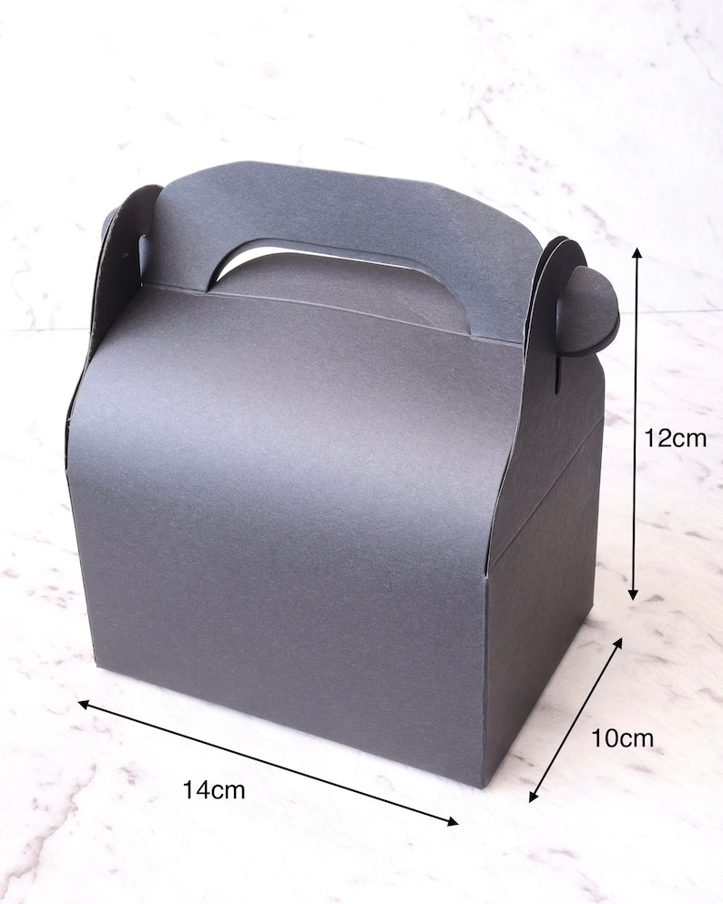 K&ouml;nnte beinhalten: Eine schwarze Pappbox mit einem Griff, die 14 cm x 10 cm x 12 cm misst.