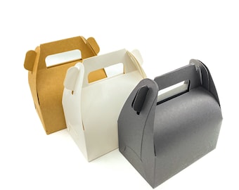 Könnte beinhalten: Drei kleine Geschenkboxen mit Griffen in einer Reihe. Die Boxen sind in drei Farben gehalten: Kraftbraun, Weiß und Grau. Jede Box hat einen Griff oben und eine gewölbte Oberseite. Die Boxen sind aus Pappe und leer.