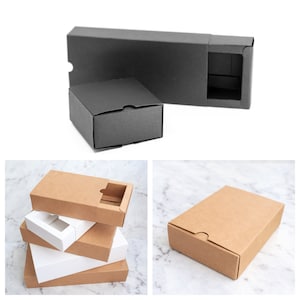 May include: A set of four cardboard boxes with a sliding drawer. The boxes are stacked on top of each other. The top box is brown, the second box is white, the third box is brown, and the bottom box is white.